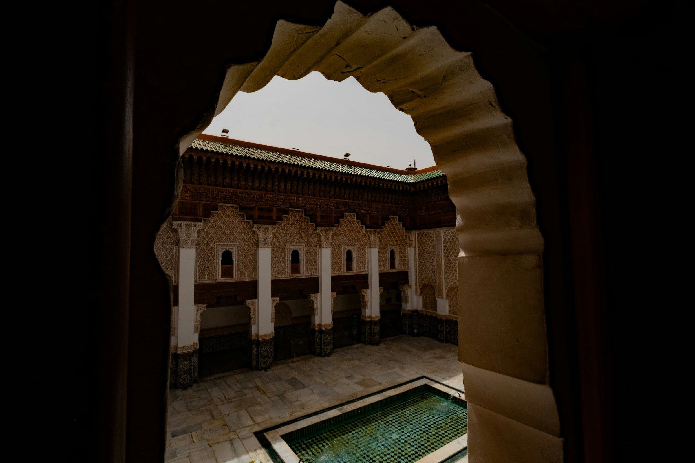 A sunlit Marrakech riad courtyard with citrus trees and a tiled plunge pool