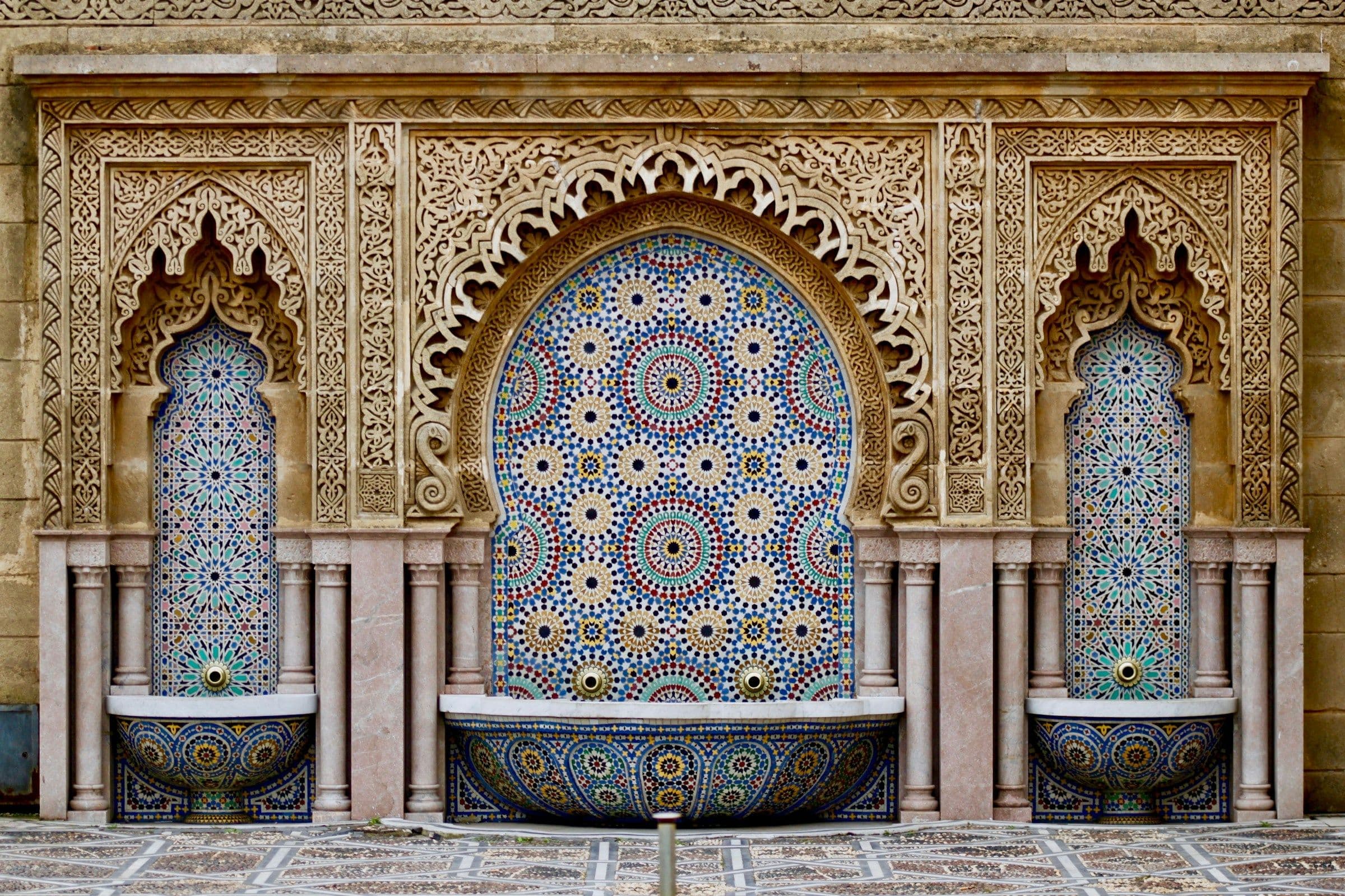A sunlit Marrakech riad courtyard with citrus trees and a tiled plunge pool
